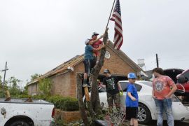 David Arce and Aldyn Rowan hang an American flag on a destroyed tree in front of their damaged house after a tornado touched down overnight in Van, Texas, USA, 11 May 2015. Multiple storms moved across the state of Texas over the weekend causing flash flooding and tornados.