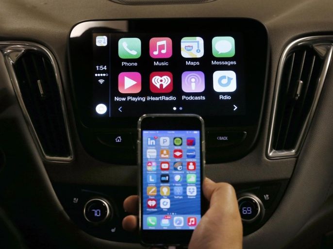 An iPhone is connected to a 2016 Chevrolet Malibu equipped with Apple CarPlay apps, displayed on the car's MyLink screen, top, during a demonstration in Detroit, Tuesday, May 26, 2015. Starting with Chevrolet this summer, many General Motors models will offer Apple’s CarPlay and Google’s Android Auto systems that link smart phones with in-car screens and electronics. (AP Photo/Paul Sancya)
