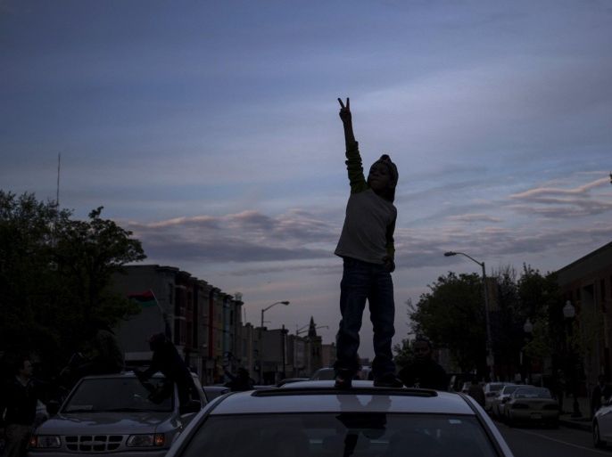 Ka'dyn Franklin, 7, reaches out to display a peace sign while celebrating from the roof of his mother's vehicle in west Baltimore, Maryland May 1, 2015. Baltimore residents cautiously celebrated news on Friday that six police officers involved in the arrest of Freddie Gray face criminal charges, a marked contrast to recent rioting over fraught relations between police and the African-American community. REUTERS/Adrees Latif TPX IMAGES OF THE DAY