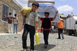Boys carry relief supplies to their families who fled fighting in the southern city of Aden, during a food distribution effort by Yemeni volunteers, in Taiz, Yemen, Saturday, May 9, 2015. Humanitarian organizations say they face challenges delivering aid to citizens affected by the ongoing conflict, because of a severe fuel shortage and difficulty accessing warehouses. (AP Photo/Abdulnasser Alseddik)