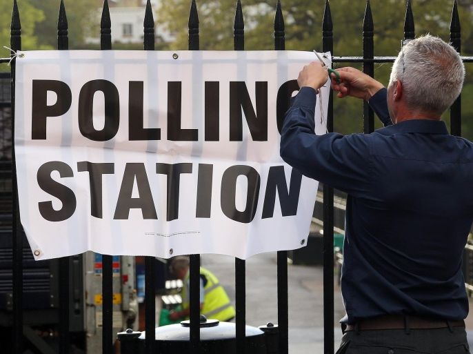 An official attaches a sign to a fence outside a polling station set up at the Cafe on the Promenade at Roath Park in Cardiff, south Wales on May 7, 2015, as Britain holds a general election. Polls opened Thursday in Britain's closest general election for decades with voters set to decide between the Conservatives of Prime Minister David Cameron, Ed Miliband's Labour and a host of smaller parties.