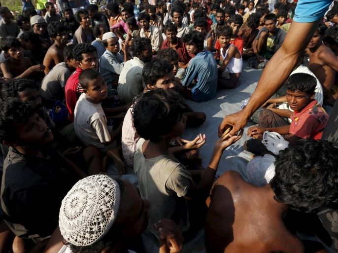 A volunteer gives biscuits to Rohingya migrants who arrived by boat, at the port of Julok village in Kuta Binje, Indonesia's Aceh Province, May 20, 2015. Hundreds of Rohingya and Bangladeshi migrants landed in Indonesia's northwestern Aceh province early on Wednesday, an Indonesian search and rescue official said. REUTERS/Beawiharta