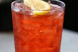 Glass of carbonated red drink with lemon slice