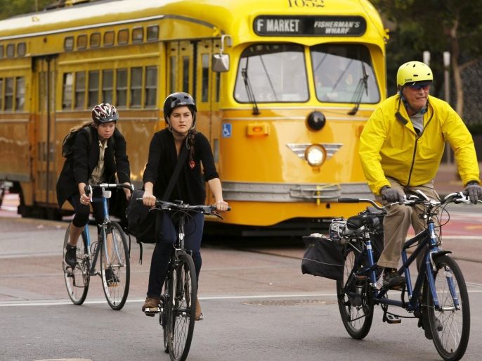 Cyclists ride with a street car in the Mid Market neighborhood during Bike to Work Day in San Francisco, California May 14, 2015. REUTERS/Robert Galbraith
