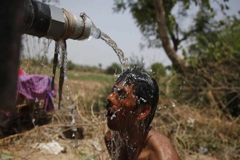 An Indian man takes bath under the tap of a water tanker on a hot day in Ahmadabad, India, Thursday, May 21, 2015. Heat wave conditions prevailed as temperature rises in many parts of India. (AP Photo/Ajit Solanki)