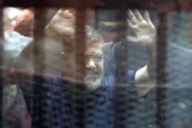 Ousted Egyptian President, Mohamed Morsi, gestures from inside a cage in the courtroom where he stood trial in Cairo, Egypt. 16 May 2015. An Egyptian court 16 May sentenced Morsi to death on charges of orchestrating a mass prison escape.