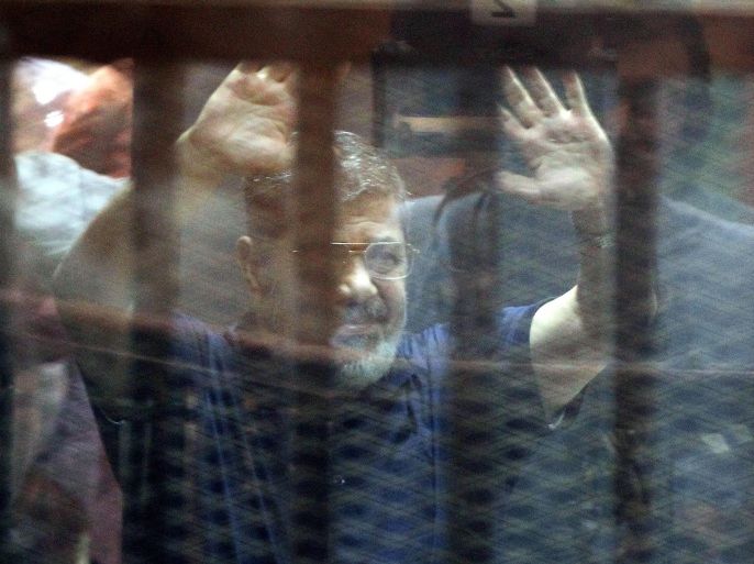Ousted Egyptian President, Mohamed Morsi, gestures from inside a cage in the courtroom where he stood trial in Cairo, Egypt. 16 May 2015. An Egyptian court 16 May sentenced Morsi to death on charges of orchestrating a mass prison escape.