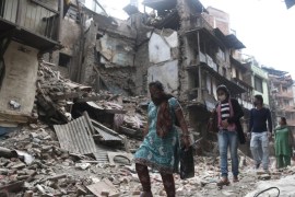 People walk between destroyed buildings on a street in Kathmandu, Nepal, 02 May 2015. The magnitude 7.8 earthquake of 25 April has killed more than 6,000 people and affected over 10 million.