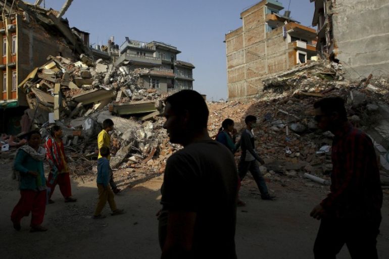 Nepalese people walk along a street near the debris of collapsed houses, a month after the April 25 earthquake in Kathmandu, Nepal May 25, 2015. REUTERS/Navesh Chitrakar