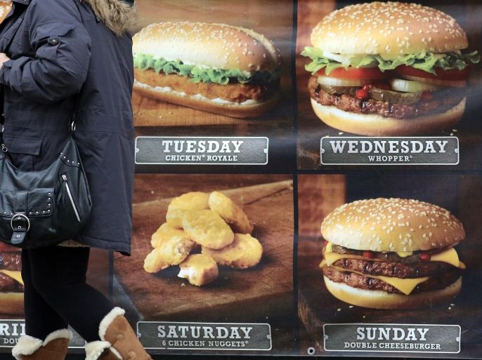 BRISTOL, ENGLAND - JANUARY 07: A woman passes an advertisement outside a fast food outlet on January 7, 2013 in Bristol, England. A government-backed TV advert - made by Aardman, the creators of Wallace and Gromit - to promote healthy eating in England, is to be shown for the first time later today. England has one of the highest rates of obesity in Europe - costing the NHS 5 billion GDP each year - with currently over 60 percent of adults and a third of 10 and 11 year olds thought to be overweight or obese.