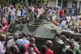 Demonstrators celebrate what they perceive to be an attempted military coup d'etat, with army soldiers riding in an armored vehicle in the capital Bujumbura, Burundi Wednesday, May 13, 2015. Police vanished from the streets of Burundi's capital Wednesday as thousands of people celebrated a coup attempt against President Pierre Nkurunziza. (AP Photo/Berthier Mugiraneza)