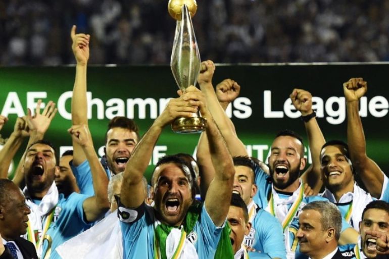ES Setif captain Farid Mellouli holds the CAF Champions League trophy on November 1, 2014 in the Mustapha-Tchaker stadium in Blida as his team mates celebrate after the football match against the Congolese AS Vita Club. Algerians Entente Setif won the CAF Champions League Saturday despite being held 1-1 at home by Congolese V Club in the second leg of the final. AFP PHOTO/FAROUK BATICHE