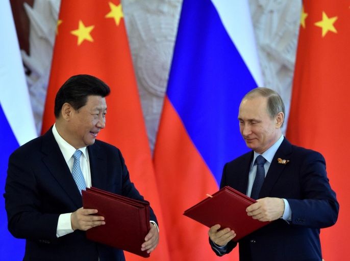 Russian President Vladimir Putin (R) and his Chinese counterpart Xi Jinping exchange documents during a signing ceremony at the Kremlin in Moscow on May 8, 2015. AFP PHOTO / KIRILL KUDRYAVTSEV