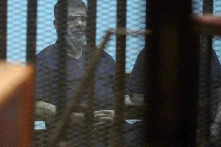 Ousted Egyptian President Mohammed Morsi sits behind glass in a courtroom, in a converted lecture hall in the national police academy in an eastern Cairo suburb, Egypt, Saturday, May 16, 2015. An Egyptian court on Saturday sentenced ousted President Mohammed Morsi to death over his part in a mass prison break that took place during the 2011 uprising that toppled Hosni Mubarak. (AP Photo/Ahmed Almalky)
