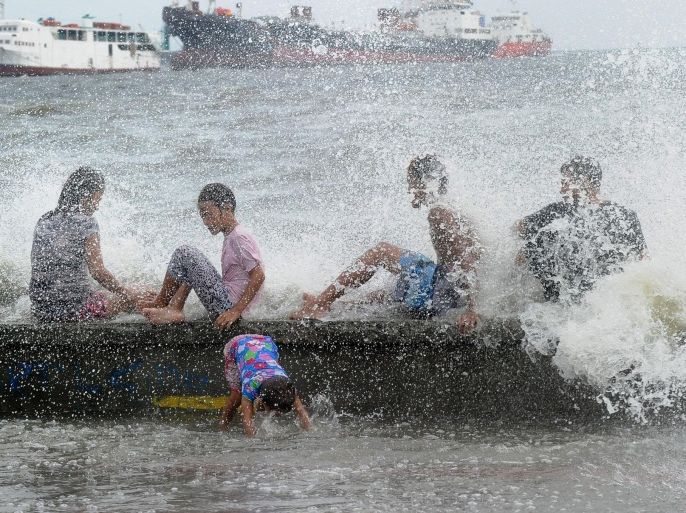 Residents along Manila Bay play in the waves created by nearby Typhoon Noul on May 10, 2015 as it approaches the northern Philippines. More than 2,000 people were fleeing their homes as Typhoon Noul approached the northern Philippines on May 10, triggering warnings of possible flash floods, landslides and tsunami-like storm surges. AFP PHOTO / Jay DIRECTO