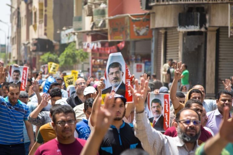 GIZA, EGYPT - MAY 1: Egyptian demonstrators who call themselves as 'Anti-Coup demonstrators', carry former Egyptian president Mohamed Morsi's posters as they stage an anti-government protest during May Day, International Workers' Day in Giza, Egypt on May 1, 2015.