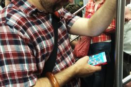 A man plays a game on a phablet while riding a subway train in New York City.