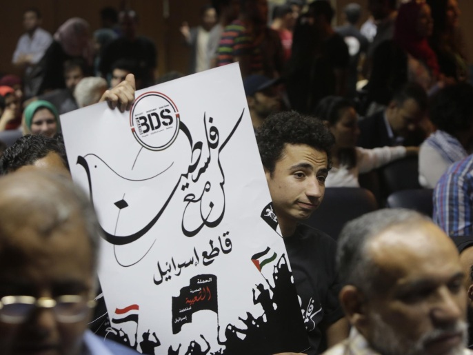 ‪(أسوشيتد برس)‬ مصري يرفع ملصقا يدعو لمقاطعة إسرائيل أثناء افتتاح حملة المقاطعة بمصر أبريل/نيسان الماضي