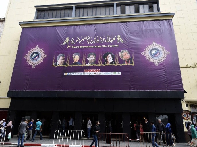 Algerians walk past a cinema bearing a poster advertising Oran's 8th International Arab Film Festival in the Algerian coastal city of Oran on June 4, 2015. AFP PHOTO / FAROUK BATICHE