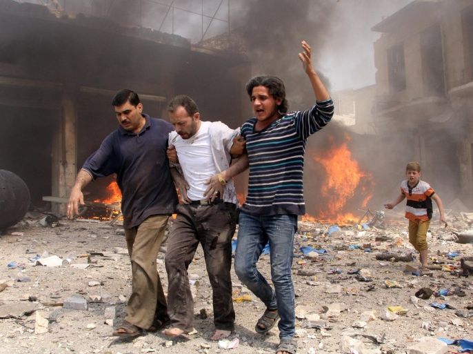 Syrian men help an injured person following a reported barrel bomb attack by Syrian government forces that hit an open market in the northern city of Aleppo, on June 2, 2015, killing and injuring people. Regime barrel bombs -- crude weapons made of containers packed with explosives -- have often struck schools, hospitals, and markets in Syria. AFP PHOTO / KARAM AL-MASRI