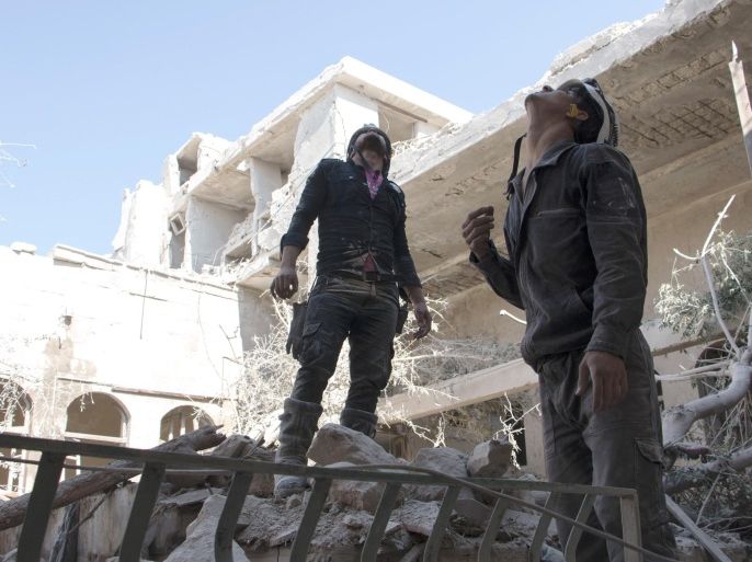 Syrian rescue workers look up to the sky in search of warplanes, on June 14, 2015, in the Jallum neighbourhood in the northern Syrian city of Aleppo, following a reported barrel bomb attack by Syrian government forces. Regime barrel bombs -- crude weapons made of containers packed with explosives -- have often struck schools, hospitals, and markets in Syria, despite condemnation by rights groups. AFP PHOTO / KARAM AL-MASRI