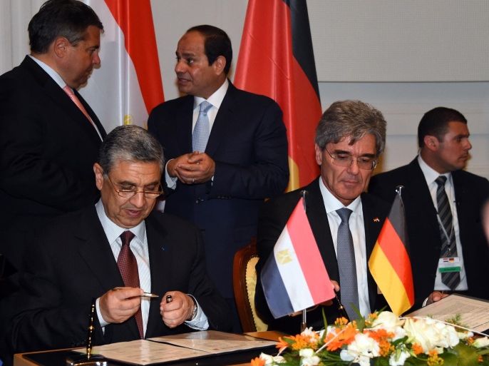 Siemens CEO Joe Kaeser (2nd R) and Egypt's Minister for Electricity and Energy Mohamed Shaker El-Markabi (2nd L) sign a contract as German Vice Chancellor, Economy and Energy Minister Sigmar Gabriel (background, L) and Egyptian President Abdel Fattah al-Sisi (background, C) talk during the second session of the German-Egyption Joint Economic Committee on June 3, 2015 in Berlin. German Vice Chancellor, Economy and Energy Minister Sigmar Gabriel and Abdel Fattah al-Sisi attended the signing of business contracts during the meeting. AFP PHOTO / TOBIAS SCHWARZ