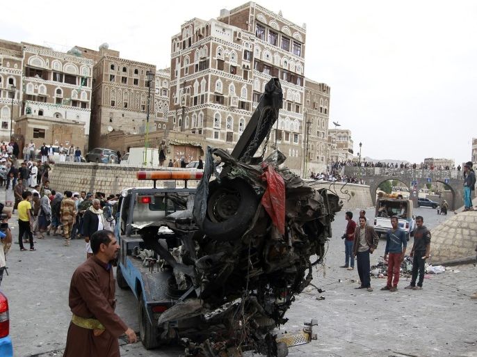 Yemenis look on as the wreckage of a vehicle is removed from the outside of the Kobbat al-Mehdi Shiite mosque in the capital Sanaa on June 20, 2015, after a car bomb targeting the area killed two people. The explosion in Sanaa, controlled by Iran-backed Shiite Huthi rebels, went off outside the mosque as Shiite Muslims emerged from midday prayers, witnesses and security sources said. AFP PHOTO / MOHAMMED HUWAIS