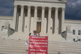 كرستين تقف بأحد لوحتها المعترضة أمام المحكمة العليا في أمريكا