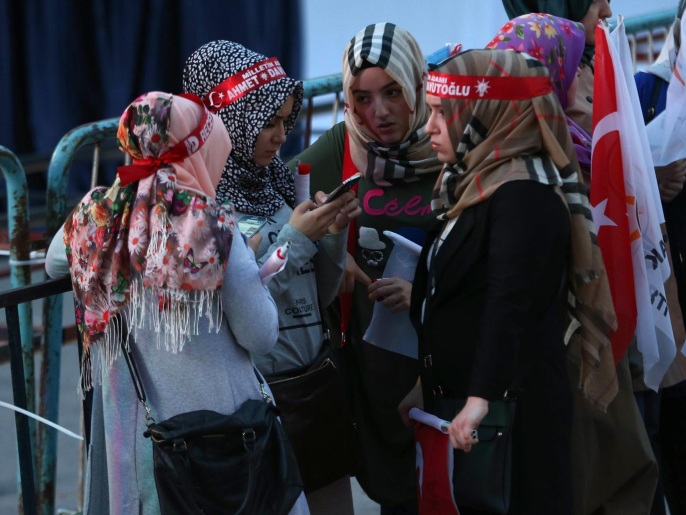 فتيات من مؤيدي حزب العدالة والتنمية يتابعن نتائج الانتخابات على الهاتف خارج مقر الحزب في أنقرة ()