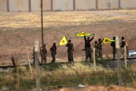 Kurdish People's Protection Units (YPG) fighters hold their movement's flag near the Akcakale crossing gate between Turkey and Syria at Akcakale in Sanliurfa province on June 15, 2015. Kurdish forces on June 15 seized a post on Syria's border with Turkey, a vital supply line to the Islamic State group, as they battle for the jihadist-held town of Tal Abyad. The Kurdish People's Protection Units (YPG) took up positions on the Syrian side of the border post after they advanced on Tal Abyad from east and west and cut the road south to Raqa, the IS de facto capital. AFP PHOTO / BULENT KILIC