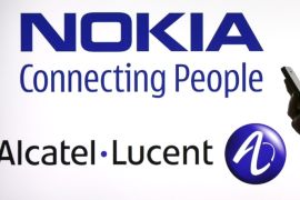 A woman holds a smartphone in front of a screen displaying both Nokia and Alcatel-Lucent logos in this file photo illustration shot in Paris, France, April 14, 2015. Alcatel-Lucent is expected to hold its AGM this week. REUTERS/Benoit Tessier/FilesGLOBAL BUSINESS WEEK AHEAD PACKAGE - SEARCH "BUSINESS WEEK AHEAD MAY 25" FOR ALL IMAGES