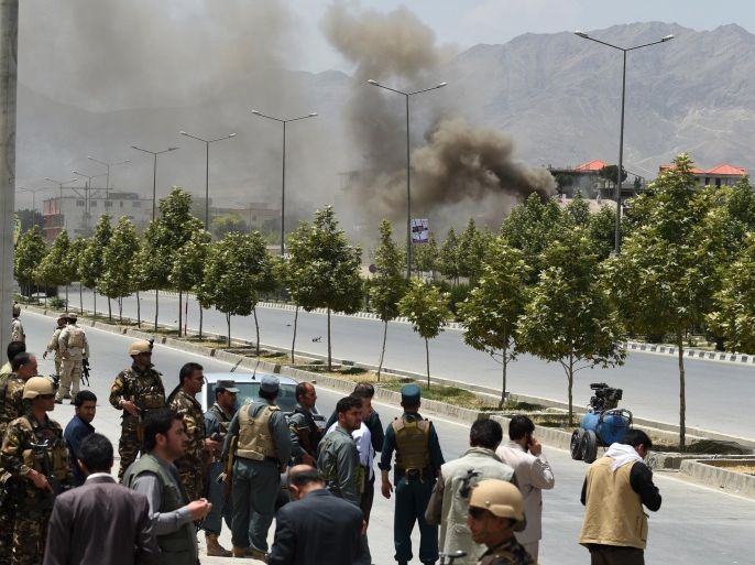 Afghan security personnel and bystanders look on as black smoke billows from the Afghan Parliament building in Kabul on June 22, 2015, during an attack in the Afghan capital. Taliban militants attacked the Afghan parliament on June 22, with gunfire and explosions rocking the building, sending lawmakers running for cover in chaotic scenes relayed live on television.The insurgents tried to storm the complex after triggering a car bomb but were repelled and have taken position in a partially-constructed building nearby, officials said about the ongoing attack. All MPs were safely evacuated after the attack, which came as the Afghan president's nominee for the crucial post of defence minister was to be introduced in parliament. AFP PHOTO / SHAH Marai