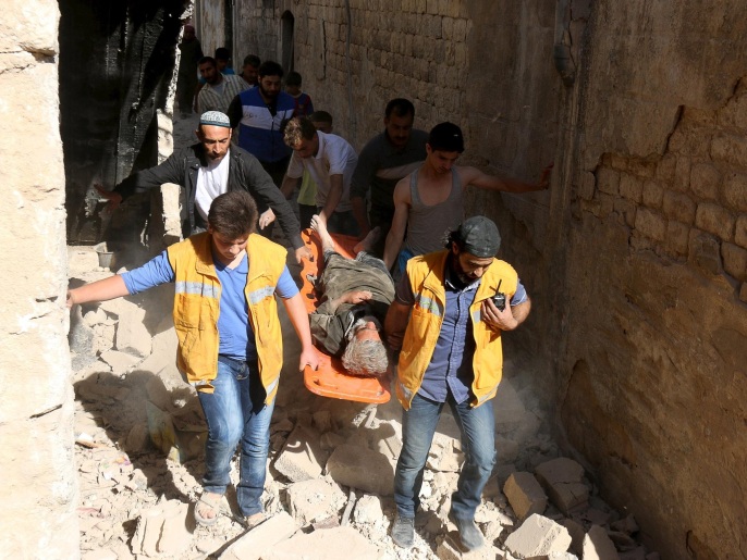 أفراد من الدفاع المدني في حلب ينقلون شيخاً جريحاً في محفة بعد أُصابته جراء سقوط برميل متفجر (رويترز)