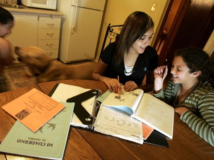 23/11/06-BNP-SPANISH LESSONS-Chantal Cabrera, 14, left, studying her Spanish with her younger sister and classmate, Ally, 10, right at the kitchen table in their family home in Toronto. Their younger brother, Daniel, 3, was running around with the family dog, and looking on with curiosity. Their father's family is from the Dominican Republic, and their grandparents only speak Spanish, so last year Chantal became one of only two graduates of the Canadian Martyrs International Languages Program.
