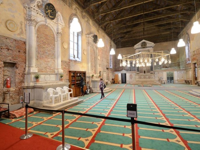 In this picture taken on May 15, 2015 and made available on Friday, May 22, 2015, people walk inside the former Misericordia Abbey in Venice, Italy, as the plaque reads ' zakat ' (donations). Venice officials have ordered the closure of a working mosque set up as Iceland's exhibit for the 56th Venice Biennale contemporary art fair in what was once a Catholic church. (AP Photo/Luigi Costantini)