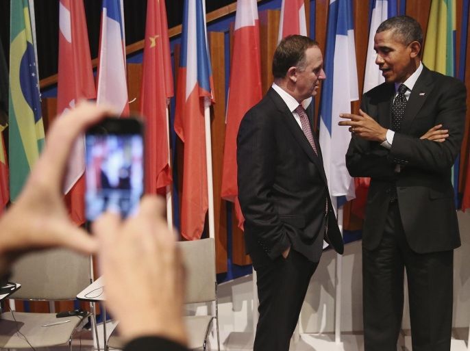 A person takes a picture with a mobile phone of U.S. President Barack Obama, right, talking with New Zealand's Prime Minister John Key, left, after the closing session of the Nuclear Security Summit (NSS) in The Hague, Netherlands, Tuesday, March 25, 2014. (AP Photo/Sean Gallup, Pool)