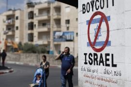 Palestinians walk past a sign painted on a wall in the West Bank biblical town of Bethlehem on June 5, 2015, calling to boycott Israeli products coming from Jewish settlements. The international BDS (boycott, divestment and sanctions) campaign, that pushes for a ban on Israeli products, aims to exert political and economic pressure over Israel's occupation of the Palestinian territories in a bid to repeat the success of the campaign which ended apartheid in South Africa. AFP PHOTO / THOMAS COEX