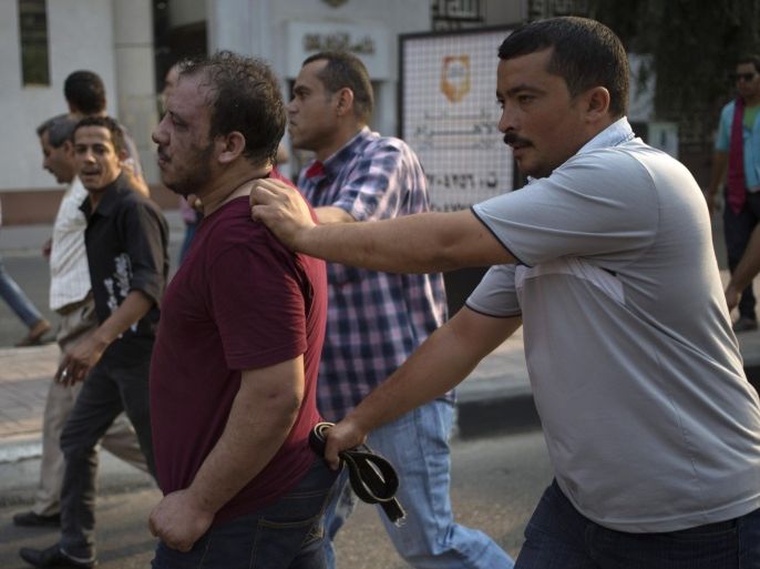 FILE - In this Sunday, Oct. 6, 2013 file photo, Egyptian security forces detain a wounded, suspected supporter, center, of ousted President Mohammed Morsi during clashes in Cairo, Egypt. Egypt’s crackdown on Islamists has jailed 16,000 people over the past eight months in the country’s biggest round-up in nearly two decades, according to previously unreleased figures from security officials. Rights activists say reports of abuses in prisons are mounting, with prisoners describing systematic beatings and miserable conditions for dozens packed into tiny cells. (AP Photo/Hassan Ammar, File)