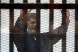 Deposed President Mohamed Mursi greets his lawyers and people from behind bars after his verdict at a court on the outskirts of Cairo June 16, 2015. An Egyptian court sentenced Mursi to death on Tuesday over a mass jail break during the country's 2011 uprising and issued sweeping punishments against the leadership of Egypt's oldest Islamic group. REUTERS/Asmaa Waguih