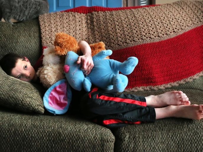 ADVANCE FOR SUNDAY MARCH 29 AND THEREAFTER - Malachi Cole, 10, finds comfort in an armful of his stuffed animals while watching the UI basketball game with his dad John Cole at their Columbus home on Friday, March 13, 2015. Malachi was born in 2004 with fetal alcohol syndrome and later diagnosed with autism, ADHD, anxiety disorder and developmental delays. He wasn't getting the services he so desperately needed and acted out to the point that the Coles were afraid of him. In 2013, the Coles were frustrated and didn't know what to do. They joined the Children's Mental Health Initiative, a joint effort among state and local agencies. Today, Malachi is making progress. He's learning coping skills and getting a host of services that seem to be making a difference. (AP Photo/The Indianapolis Star, Matt Detrich) NO SALES