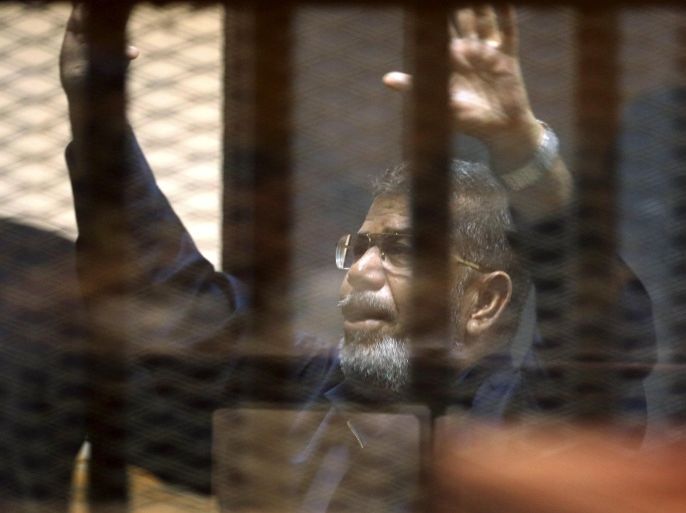Deposed Egyptian President Mohamed Mursi greets other Muslim Brotherhood members also behind bars after their verdict at a court on the outskirts of Cairo, Egypt June 16, 2015. An Egyptian court sentenced Mursi to death on Tuesday on charges of killing, kidnapping and other offences during a 2011 mass jail break.The general guide of the Muslim Brotherhood, Mohamed Badie, and four other Brotherhood leaders were also handed the death penalty. More than 80 others were sentenced to death in absentia. REUTERS/Asmaa Waguih