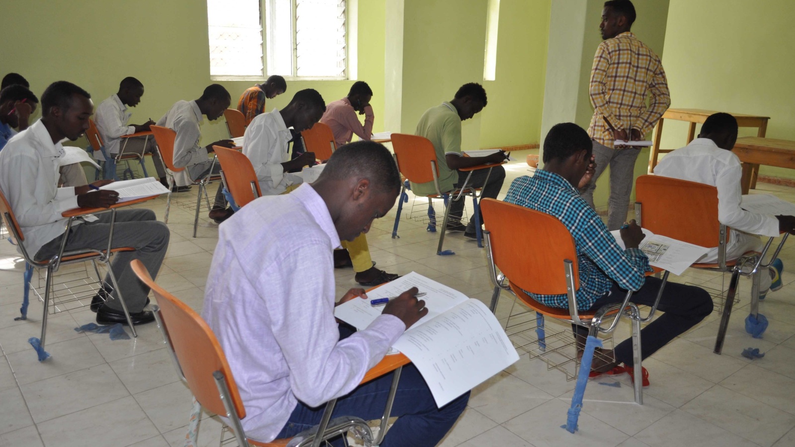‪مراقب يتجول بين الطلاب أثناء امتحانات الثانوية العامة الموحدة بالصومال‬ (الجزيرة)