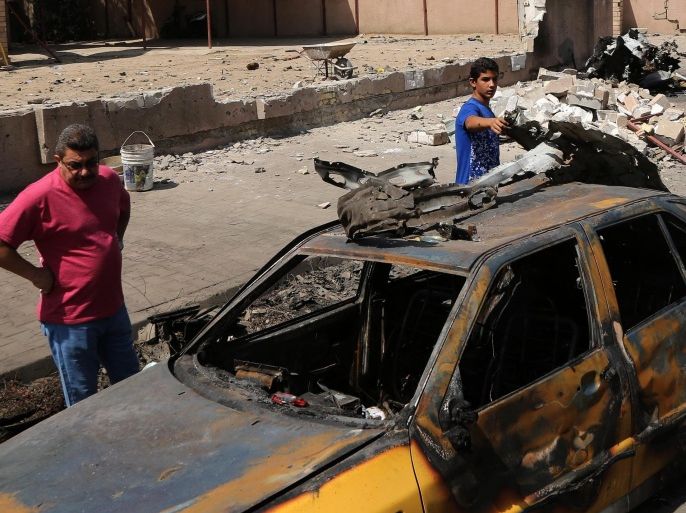People inspect the scene of after an explosion hit a busy commercial area in Baghdad, Iraq Monday, July 13, 2015. A string of car bombs and explosive belts attacks across Baghdad killed and wounded dozens of people on Sunday, Iraqi officials said. (AP Photo/Karim Kadim)