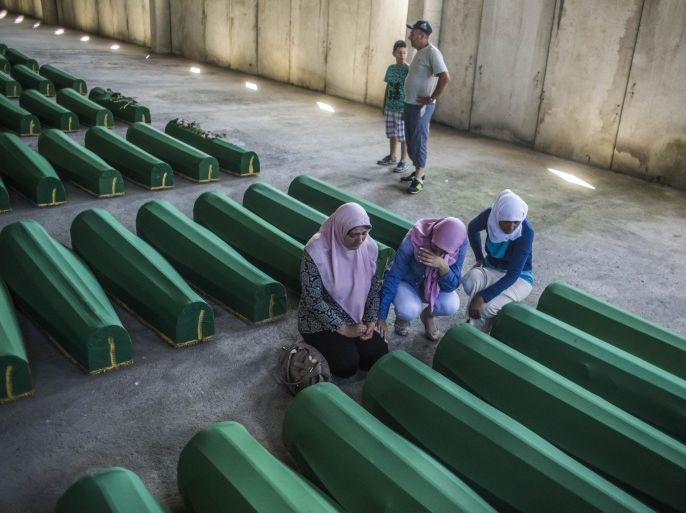 SREBRENICA, BOSNIA AND HERZEGOVINA - JULY 10: Women mourn over a coffin among 136 coffins of victims of the 1995 Srebrenica massacre in the hall at the Potocari cemetery and memorial near Srebrenica on July 10, 2015 in Srebrenica, Bosnia and Herzegovina. The newly-identified remains of another 136 victims from Srebrenica massacre will be buried at the ceremony on July 11, 2015 on the 20th anniversary of the massacre. At least 8,3000 Bosnian Muslim men and boys who had sought safe heaven at the U.N.-protected enclave at Srebrenica were killed by members of the Republic of Serbia (Republika Srpska) army under the leadership of General Ratko Mladic, who is currently facing charges of war crimes at The Hague, during the Bosnian war in 1995.