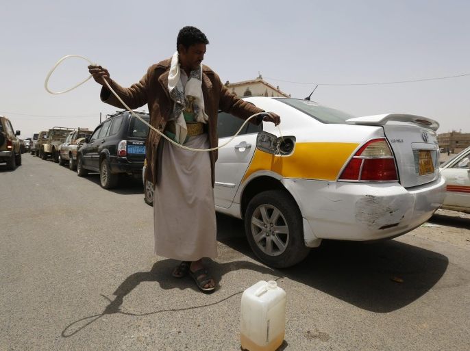 A motorist holds a tube after he sucked little oil from his car as the car lines up at a crowded petrol station during ongoing fuel shortages in Sana'a, Yemen, 18 May 2015. Yemen is experiencing fuel shortages since the Saudi-led coalition began airstrikes on Houthi rebels positions 25 March.