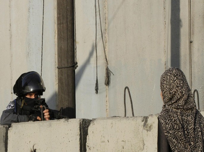 An Israeli soldier near Palestinian women, waiting next to the Israeli West Bank seperation barrier - wall, to make their way to attend the third Friday prayer of Ramadan in Jerusalem's al-Aqsa mosque, near the Qalandia checkpoint close to the West Bank city of Ramallah, 03 July 2015. Muslims around the world celebrate the holy month with prayers and readings from the Koran as they fast from eating, drinking, smoking and all sexual relations from dawn till dusk.