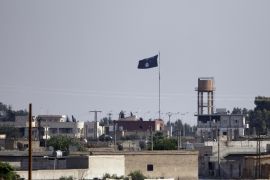 SANLIURFA, TURKEY - JUNE 15: An Islamic State flag flies in the northern Syrian town of Tel Abyad as it is pictured from the Turkish border town of Akcakale, in Sanliurfa province, Turkey, June 15, 2015. Members of the Syrian Kurdish YPG militia took positions on the outskirts of the Islamic State stronghold of Tel Abyad. Thousands of Syrians cut through a border fence and crossed over into Turkey on Sunday, fleeing intense fighting in northern Syria between Kurdish fighters and jihadis.According to Turkish security officials 10,000 people to come across from Syria in last two days.