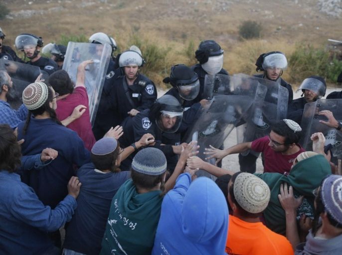 Israeli security forces scuffle with Israeli settlers who refuse to leave during the evacuation of a 24 housing units illegal building site where settlers had barricaded at the Jewish settlement of Beit El, near the West Bank town of Ramallah, early 28 July 2015. Israel's Supreme Court earlier had ruled to demolish the 24 housing units in the settlement claiming they were illegally built on private Palestinian land.