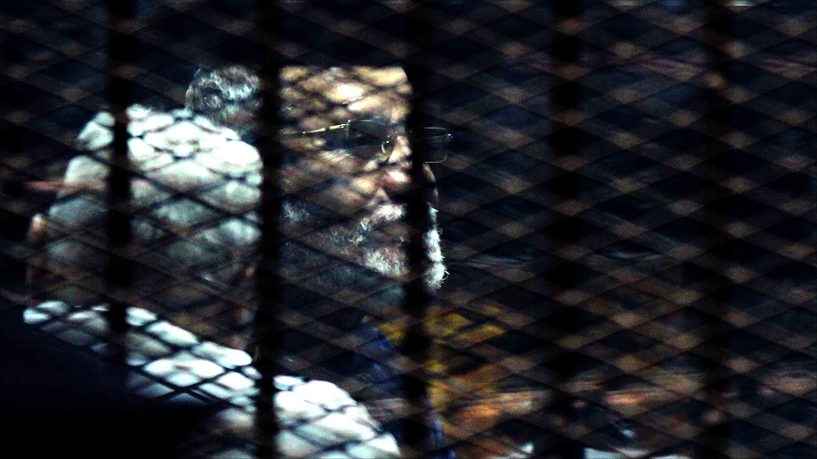 مرشد الإخوان محمد بديع داخل قفص الاتهام في قضية مكتب الإرشاد (الجزيرة-أرشيف)
