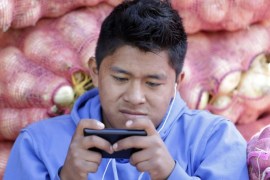In this Aug. 24, 2014, photo, a young man texts a message on his mobile phone while working at the Mayorista Market in Quito, Ecuador. Ecuador's Central Bank is getting ready to use electronic currency in which consumers will initially be able to use it to make and receive payments using their cellphones. Ecuador is heralding its plans to create the world’s first government-issued digital currency, which some analysts believe could ultimately replace the country’s existing currency, the U.S. dollar, which the government cannot control. (AP Photo/Dolores Ochoa)